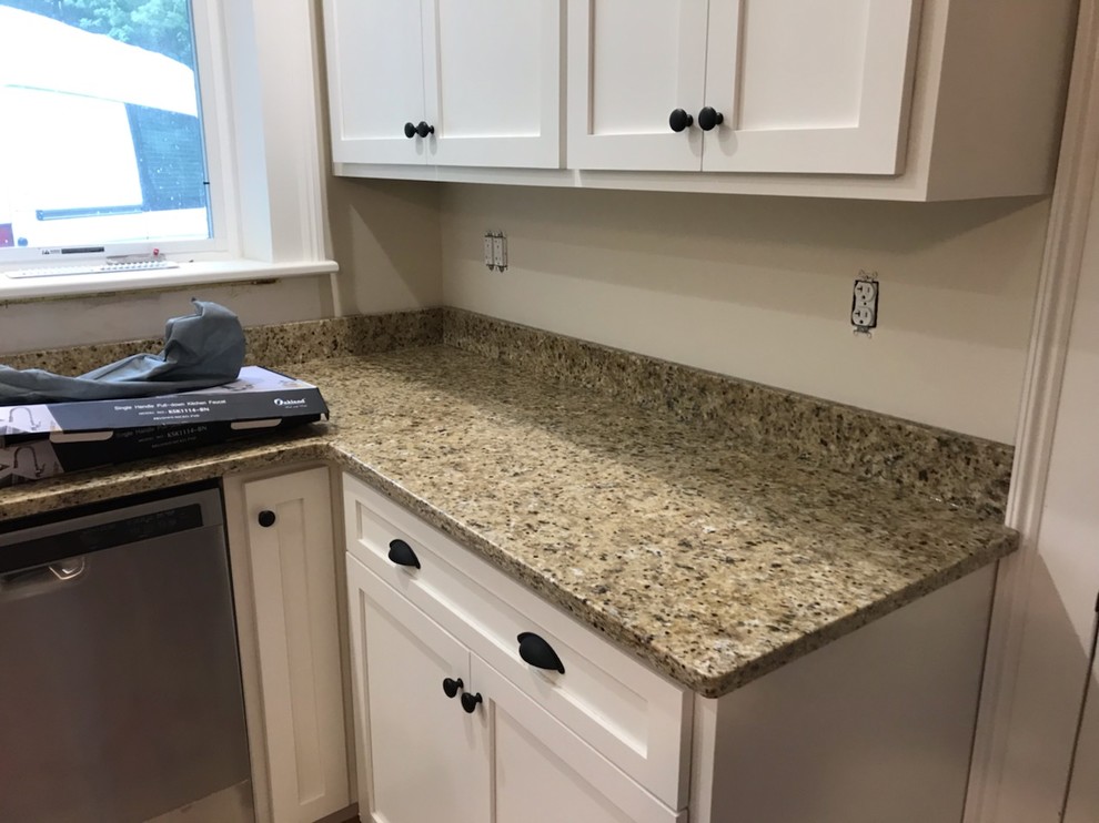 Design ideas for a mid-sized l-shaped separate kitchen in Other with a farmhouse sink, recessed-panel cabinets, white cabinets, granite benchtops, stainless steel appliances, linoleum floors, no island, brown floor and brown benchtop.