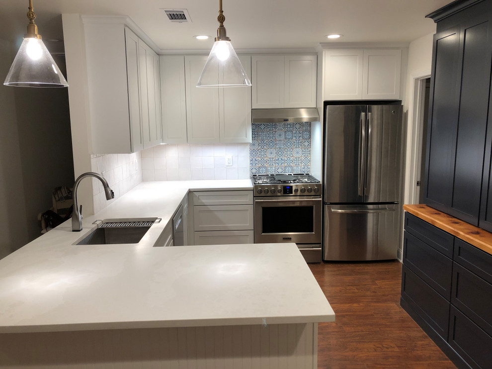 Photo of a mid-sized transitional u-shaped open plan kitchen in New Orleans with an undermount sink, shaker cabinets, white cabinets, quartzite benchtops, white splashback, ceramic splashback, stainless steel appliances, medium hardwood floors, a peninsula, brown floor, white benchtop and exposed beam.