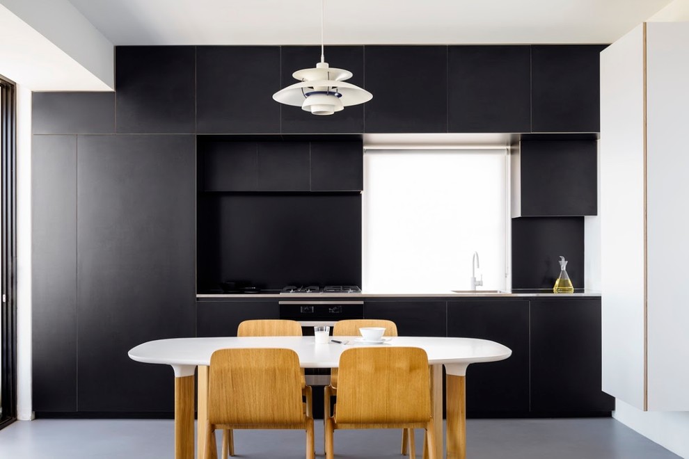 Small contemporary single-wall separate kitchen in Sydney with an undermount sink, black splashback, stainless steel appliances, concrete floors, grey floor, black cabinets, stainless steel benchtops and no island.
