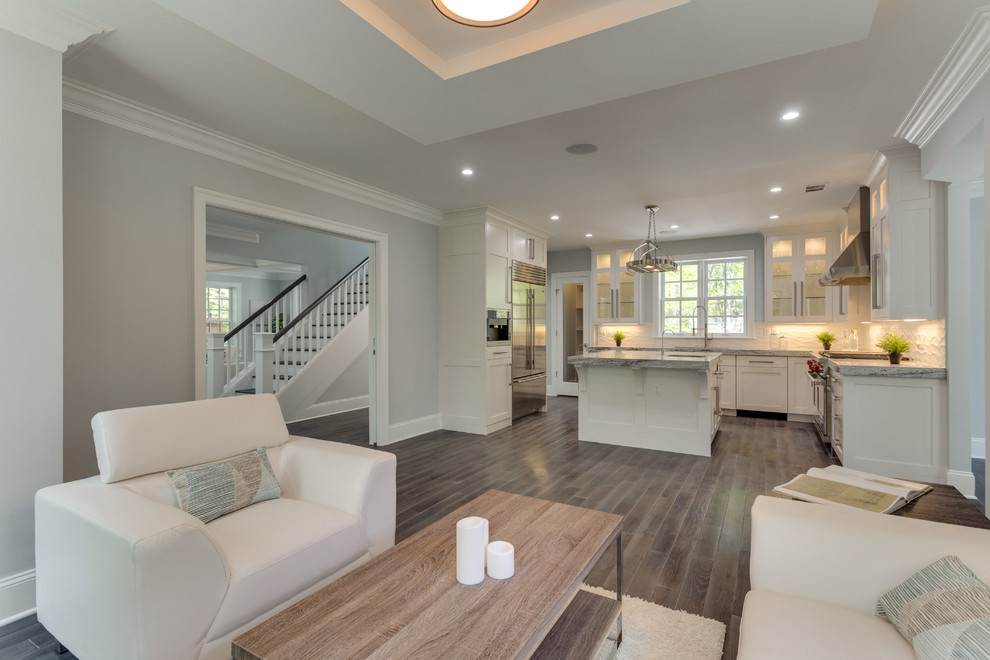 Example of a large transitional l-shaped medium tone wood floor open concept kitchen design in DC Metro with a double-bowl sink, shaker cabinets, white cabinets, marble countertops, white backsplash, porcelain backsplash, stainless steel appliances and an island