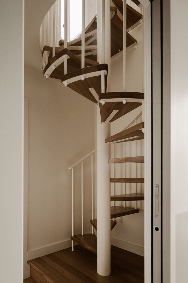 Foto de escalera de caracol mediterránea grande sin contrahuella con escalones de madera y barandilla de metal