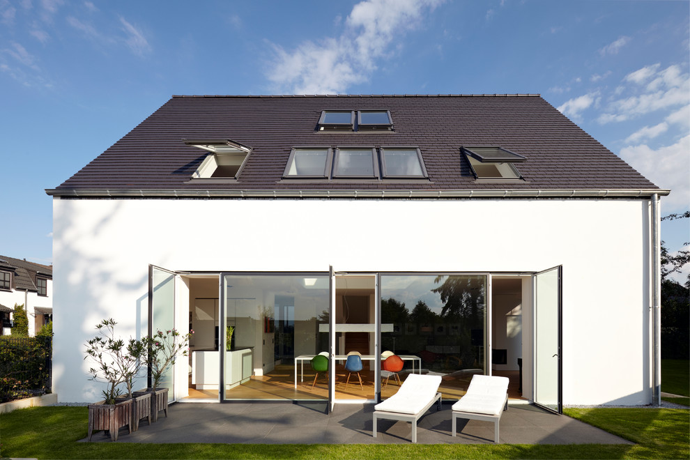 Large contemporary three-storey white house exterior in Cologne with a gable roof and a tile roof.