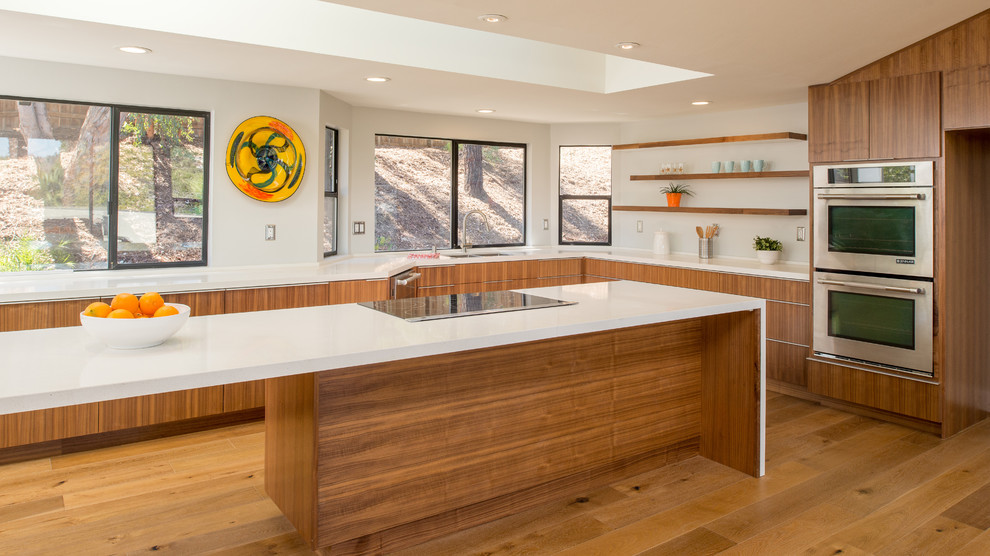 Inspiration for a large midcentury u-shaped open plan kitchen in San Diego with medium wood cabinets, white splashback, stainless steel appliances, light hardwood floors and with island.