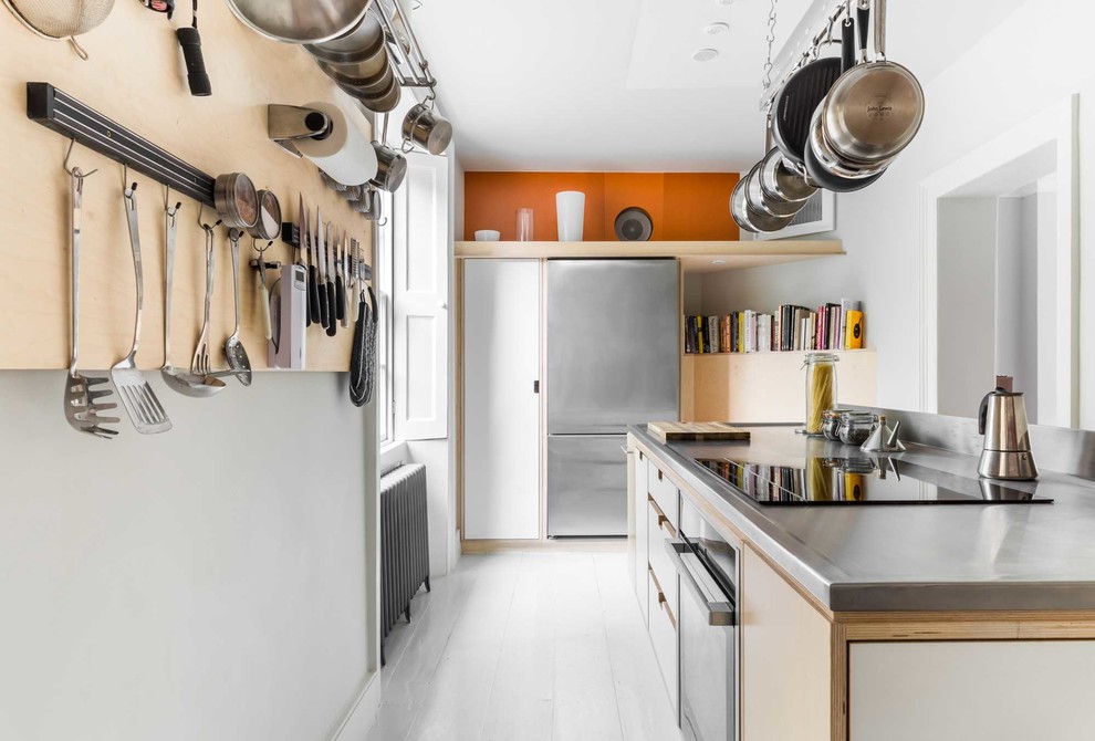 Inspiration for a mid-sized contemporary u-shaped separate kitchen in Other with flat-panel cabinets, white cabinets, stainless steel benchtops, stainless steel appliances, light hardwood floors, with island, white floor, a drop-in sink and orange splashback.