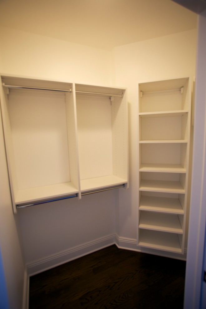 Inspiration for a small traditional gender-neutral built-in wardrobe in New York with flat-panel cabinets, white cabinets, dark hardwood floors and brown floor.