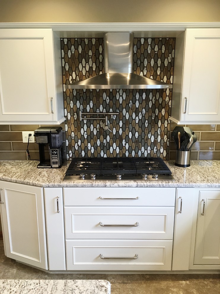 Example of a large transitional l-shaped vinyl floor and beige floor eat-in kitchen design with a double-bowl sink, recessed-panel cabinets, white cabinets, granite countertops, brown backsplash, ceramic backsplash, stainless steel appliances and an island