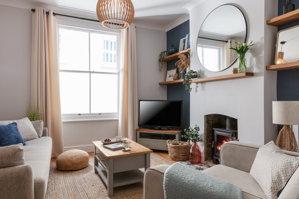 Inspiration for a medium sized scandi formal open plan living room feature wall in Cornwall with grey walls, medium hardwood flooring, a wood burning stove, a brick fireplace surround, a corner tv and brown floors.