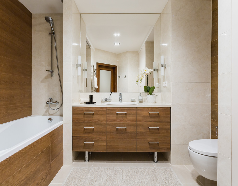 This is an example of a mid-sized contemporary master bathroom in Moscow with flat-panel cabinets, medium wood cabinets, an alcove tub, a shower/bathtub combo, a wall-mount toilet, a drop-in sink, beige walls, porcelain floors, beige tile, ceramic tile, solid surface benchtops and an open shower.