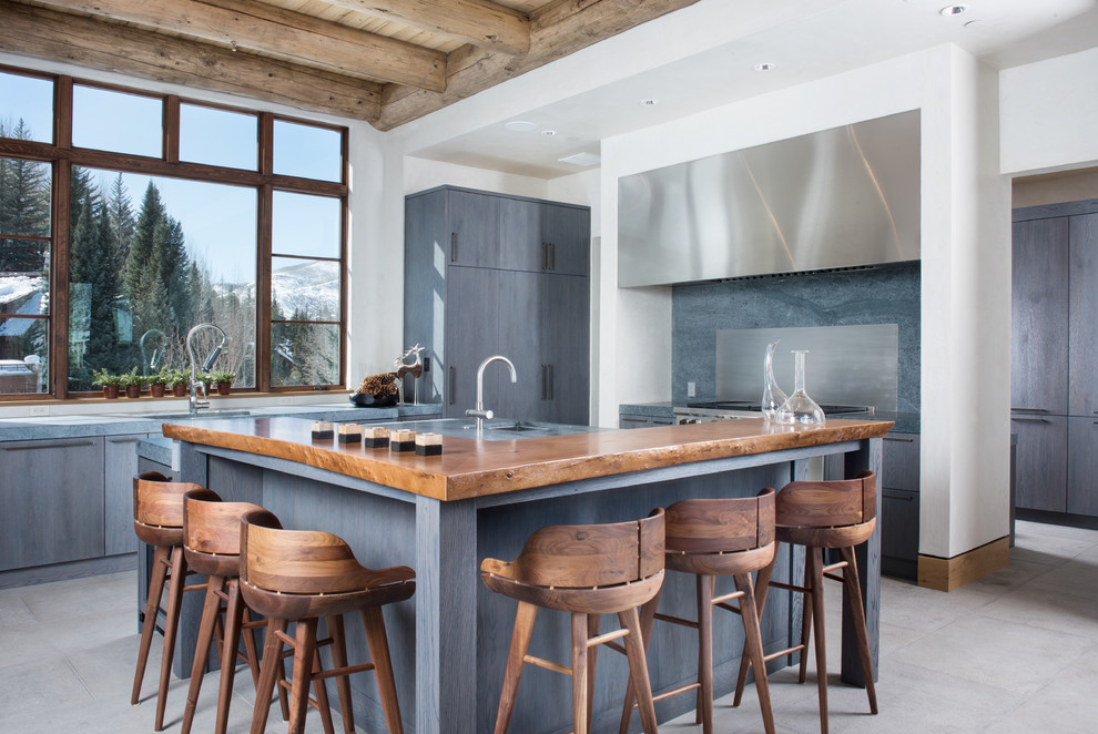 Inspiration for a large country l-shaped open plan kitchen in Denver with an undermount sink, flat-panel cabinets, blue cabinets, stainless steel appliances, wood benchtops, grey splashback, stone slab splashback, with island, grey floor and brown benchtop.