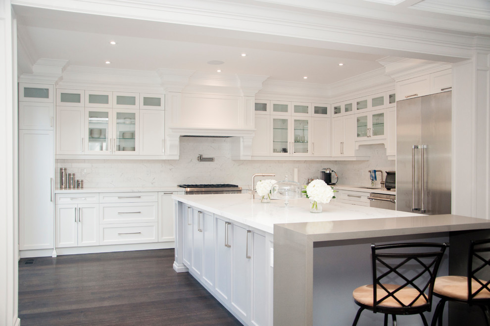 Enclosed kitchen - large transitional l-shaped dark wood floor and brown floor enclosed kitchen idea in Toronto with an undermount sink, shaker cabinets, white cabinets, quartz countertops, white backsplash, marble backsplash, stainless steel appliances, an island and white countertops