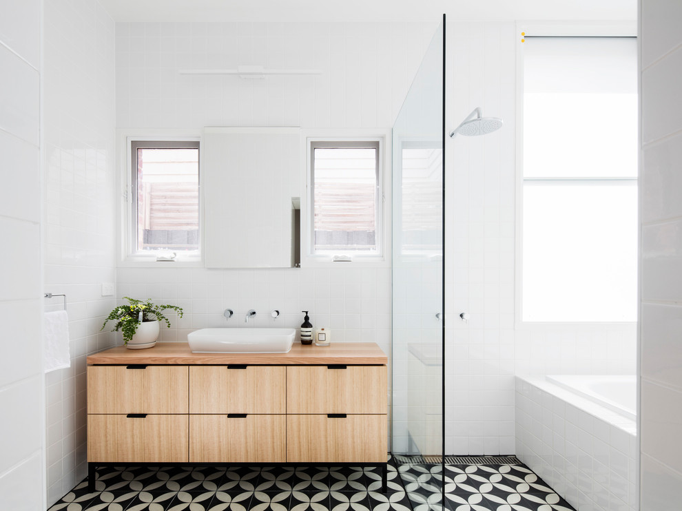 This is an example of a contemporary master bathroom in Melbourne with flat-panel cabinets, light wood cabinets, a drop-in tub, a curbless shower, white walls, a vessel sink, wood benchtops, multi-coloured floor, an open shower and brown benchtops.