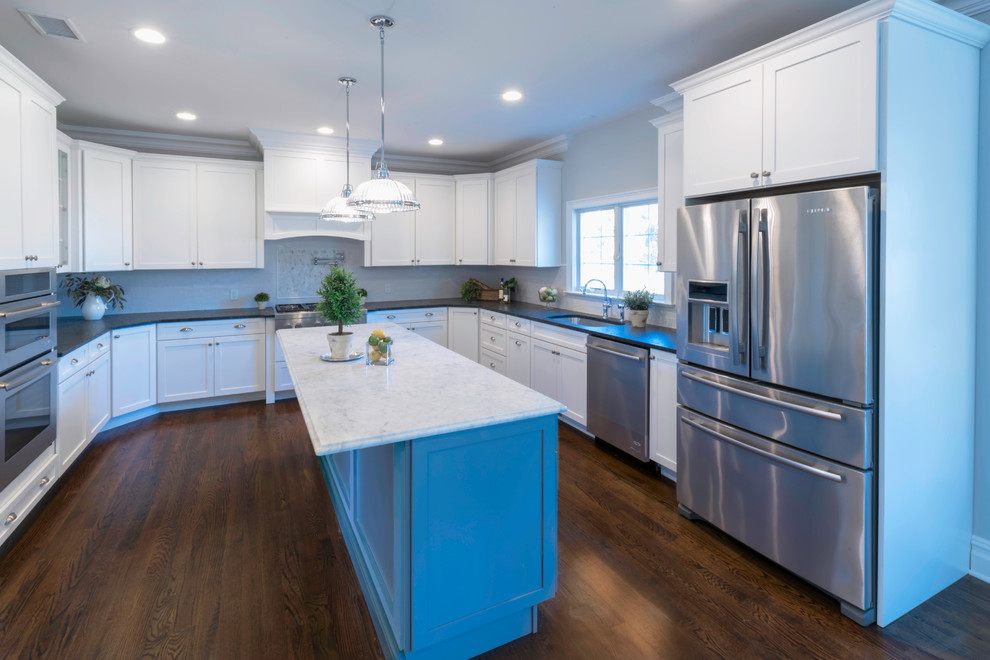 Inspiration for a large transitional u-shaped eat-in kitchen in New York with an undermount sink, shaker cabinets, white cabinets, granite benchtops, white splashback, subway tile splashback, white appliances, medium hardwood floors, multiple islands and brown floor.