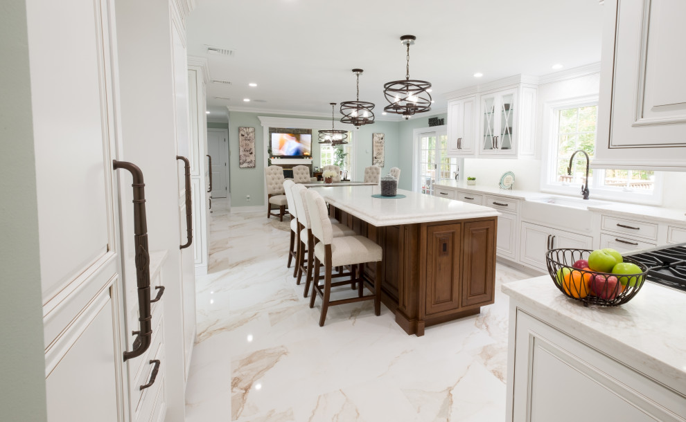 Inredning av ett klassiskt mellanstort vit vitt kök, med en rustik diskho, luckor med profilerade fronter, vita skåp, bänkskiva i kvarts, vitt stänkskydd, integrerade vitvaror, marmorgolv, en köksö och vitt golv