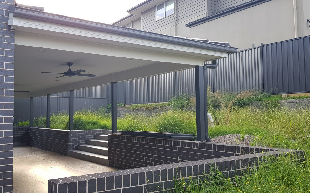 Photo of a large contemporary backyard patio in Sydney with tile and a roof extension.