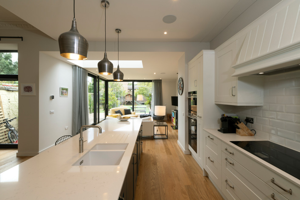 This is an example of a large traditional open plan kitchen in Edinburgh with shaker cabinets, quartzite benchtops, white splashback, subway tile splashback, panelled appliances, with island and multi-coloured benchtop.