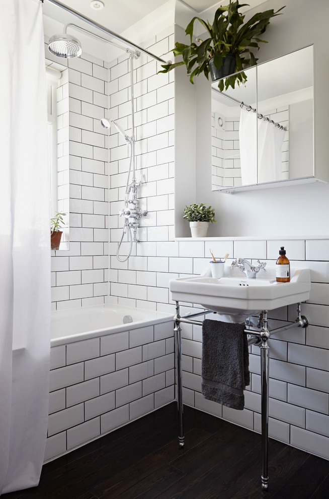 Design ideas for a traditional bathroom in London with a console sink, an alcove tub, a shower/bathtub combo, white walls, dark hardwood floors, white tile and a single vanity.