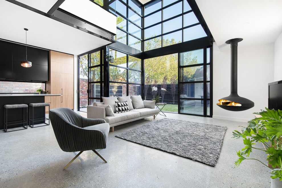 Mid-sized contemporary open concept living room in Melbourne with white walls, concrete floors, a hanging fireplace and a freestanding tv.