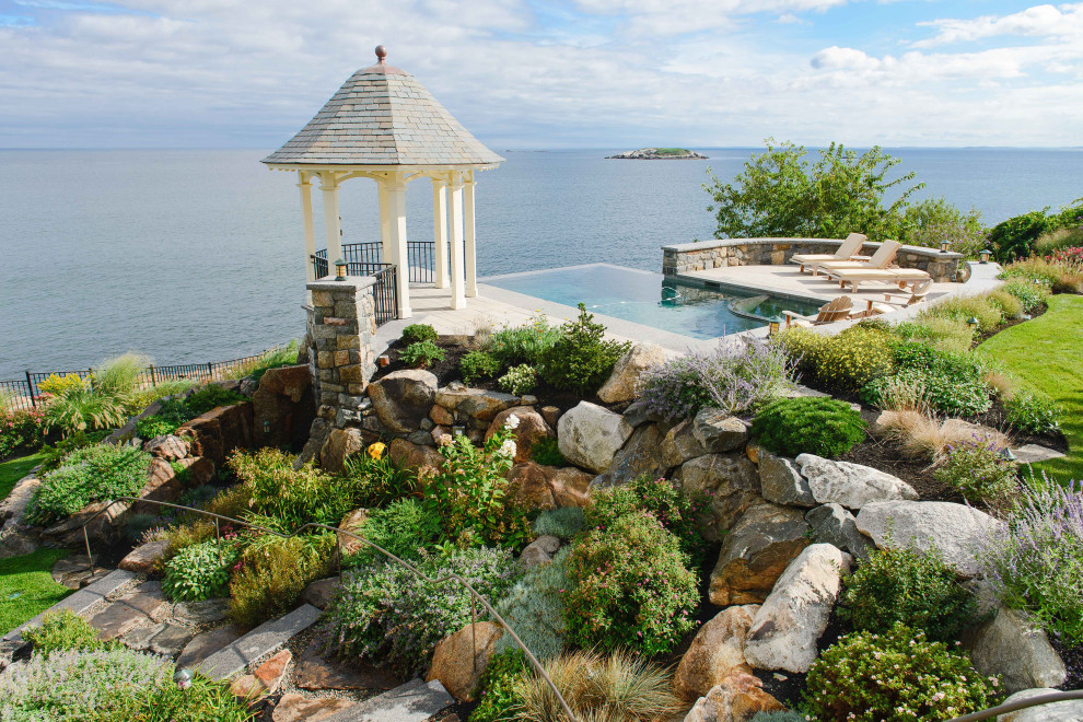 Inspiration for a mid-sized beach style backyard garden with a retaining wall and natural stone pavers.