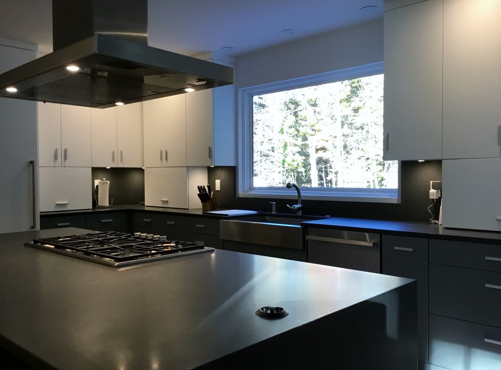 Large contemporary u-shaped open plan kitchen in Portland Maine with a farmhouse sink, flat-panel cabinets, white cabinets, quartz benchtops, grey splashback, stainless steel appliances, medium hardwood floors and with island.