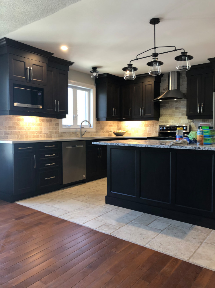Inspiration for a mid-sized transitional l-shaped limestone floor and beige floor enclosed kitchen remodel in Ottawa with an undermount sink, shaker cabinets, black cabinets, granite countertops, brown backsplash, stone tile backsplash, stainless steel appliances, an island and multicolored countertops