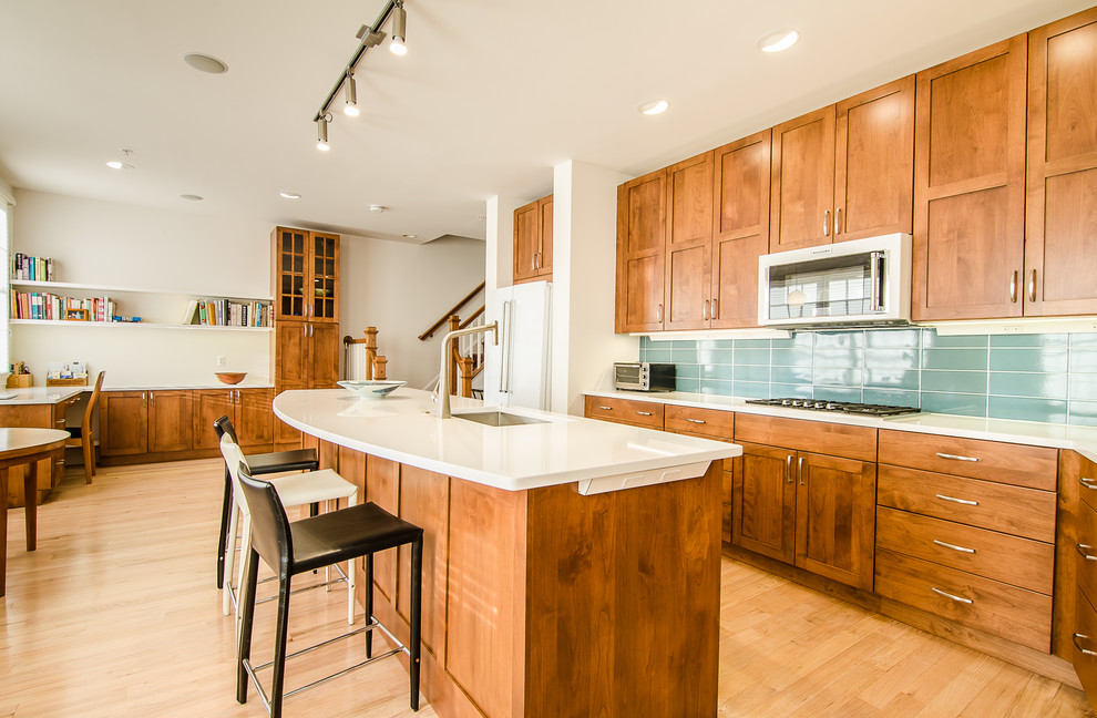 Mid-sized transitional l-shaped light wood floor eat-in kitchen photo in DC Metro with an undermount sink, flat-panel cabinets, quartz countertops, blue backsplash, glass tile backsplash, white appliances and an island