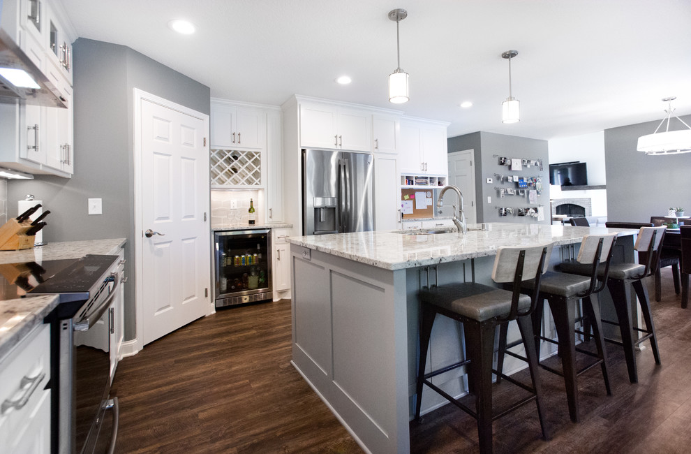 Example of a mid-sized transitional l-shaped vinyl floor and brown floor eat-in kitchen design in Minneapolis with an undermount sink, shaker cabinets, white cabinets, granite countertops, gray backsplash, ceramic backsplash, stainless steel appliances, an island and multicolored countertops