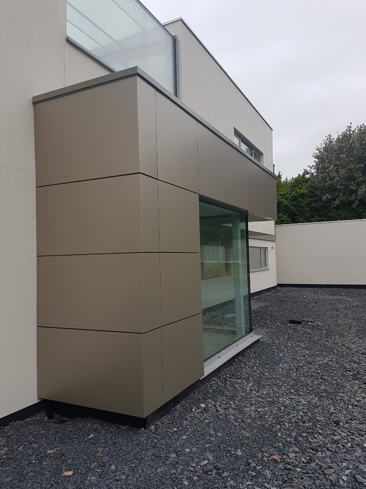 Photo of a large contemporary two-storey white exterior in Dublin with mixed siding and a flat roof.