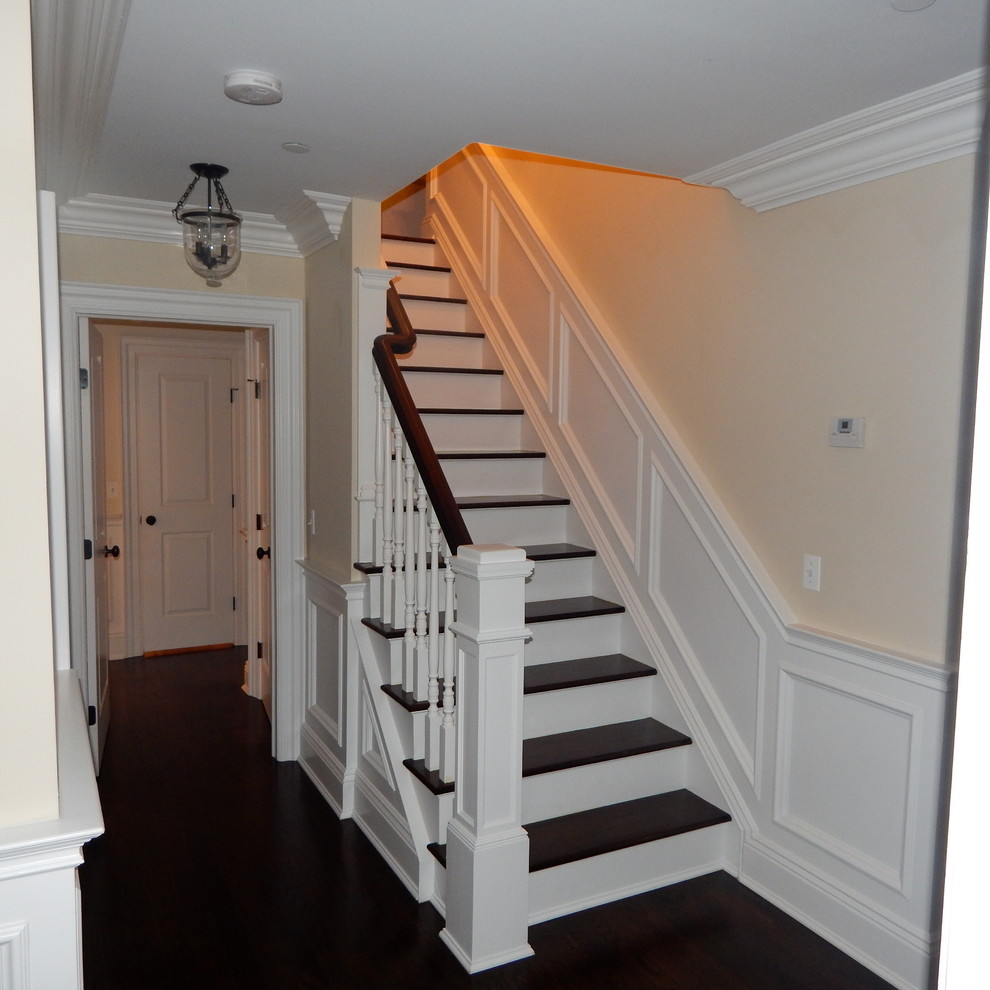 This is an example of a large transitional hallway in New York with beige walls and dark hardwood floors.