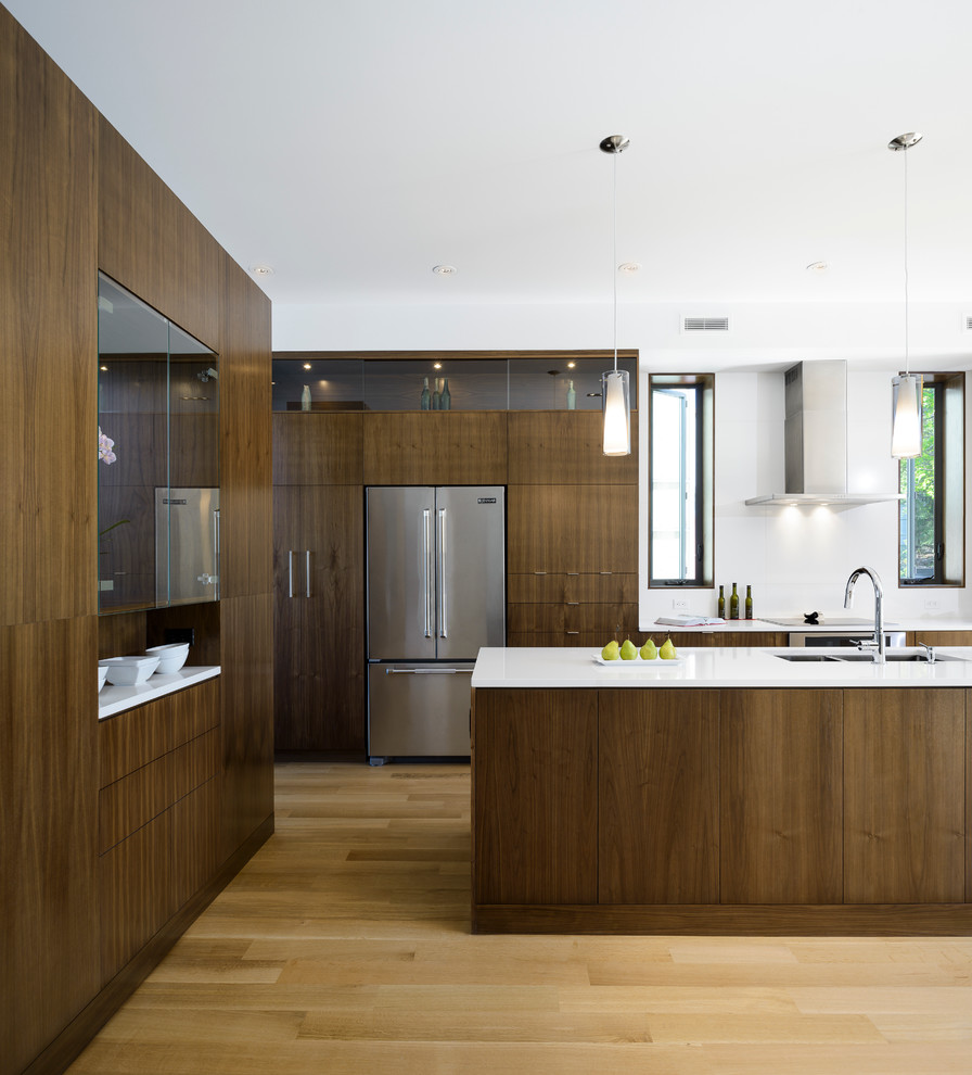 This is an example of a contemporary galley eat-in kitchen in Ottawa with a double-bowl sink, flat-panel cabinets, medium wood cabinets, quartzite benchtops and stainless steel appliances.