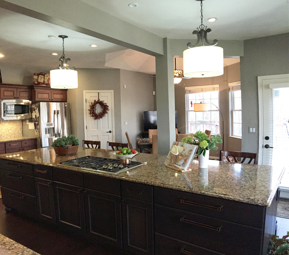 Photo of a transitional l-shaped kitchen in St Louis with an undermount sink, recessed-panel cabinets, dark wood cabinets, quartzite benchtops, beige splashback, stone tile splashback, stainless steel appliances, dark hardwood floors and with island.