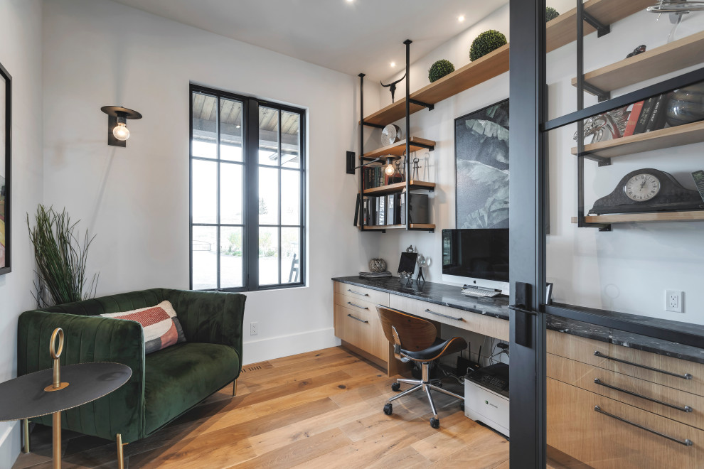 Mittelgroßes Modernes Lesezimmer mit weißer Wandfarbe, dunklem Holzboden und Einbau-Schreibtisch in Calgary