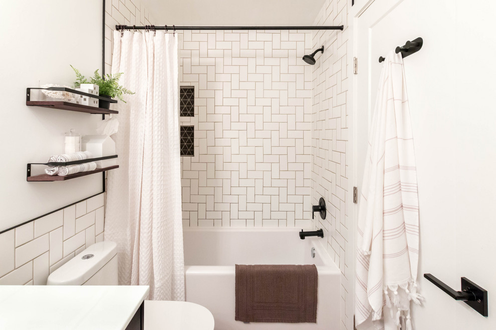 Cette photo montre une petite salle de bain moderne avec un placard à porte shaker, des portes de placard noires, une baignoire en alcôve, un combiné douche/baignoire, WC à poser, un carrelage blanc, des carreaux de céramique, un mur blanc, un sol en vinyl, un lavabo encastré, un plan de toilette en surface solide, un sol marron, une cabine de douche avec un rideau, un plan de toilette blanc, une niche, meuble simple vasque, meuble-lavabo sur pied et boiseries.