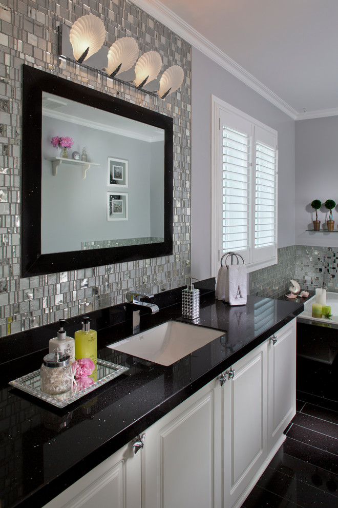 This is an example of a large modern master bathroom in Tampa with raised-panel cabinets, white cabinets, a drop-in tub, mirror tile, grey walls, porcelain floors, an undermount sink, granite benchtops and black floor.