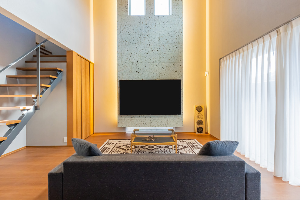 Foto de salón abierto moderno grande sin chimenea con suelo de madera en tonos medios, televisor colgado en la pared, suelo marrón, papel pintado, madera y paredes grises