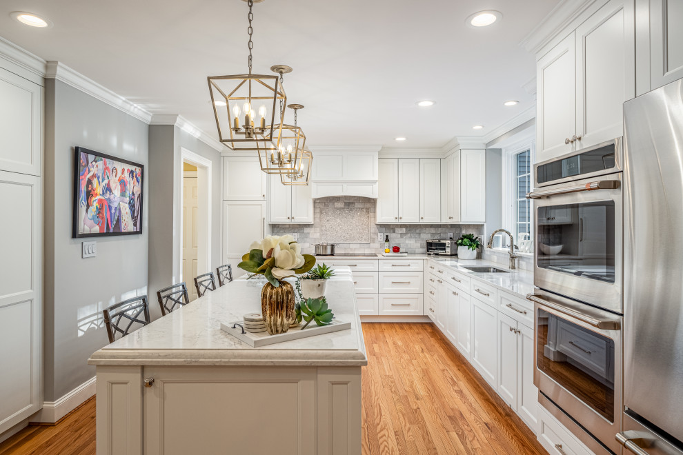 Inspiration for a large transitional single-wall brown floor enclosed kitchen remodel with an undermount sink, recessed-panel cabinets, white cabinets, gray backsplash, stainless steel appliances, an island and gray countertops
