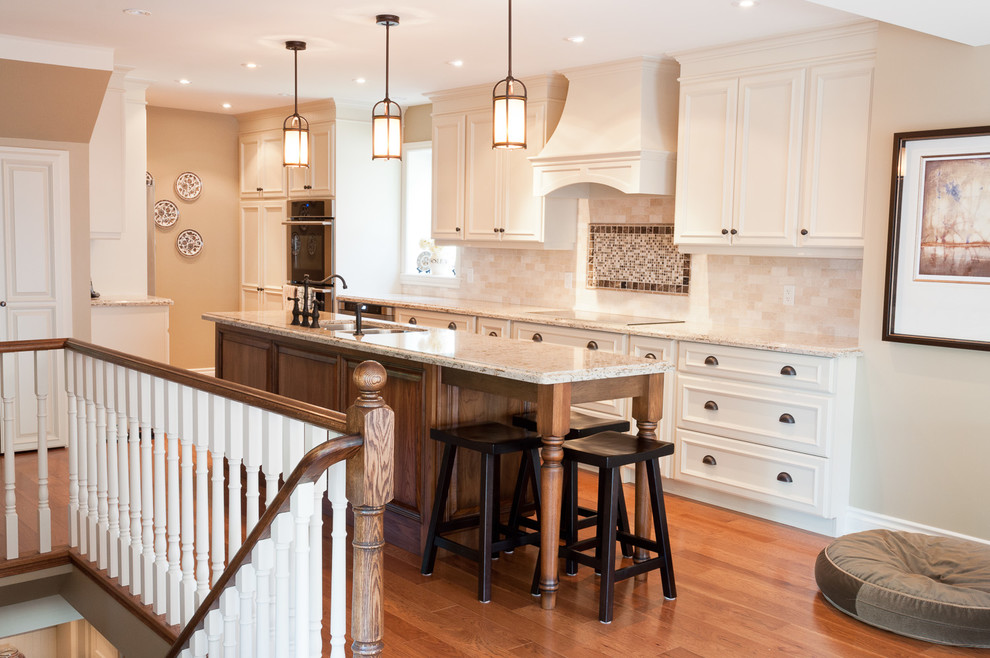 Photo of a traditional galley kitchen in Burlington with recessed-panel cabinets, white cabinets, beige splashback, stainless steel appliances, medium hardwood floors and with island.