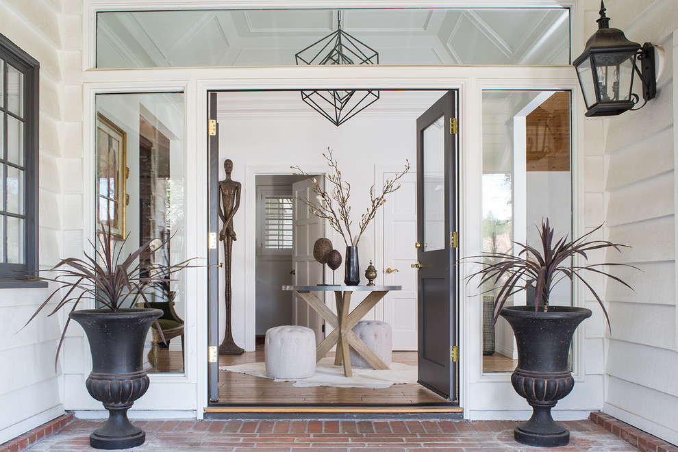 This is an example of a mid-sized eclectic foyer in Los Angeles with white walls, light hardwood floors, a double front door, a black front door and brown floor.