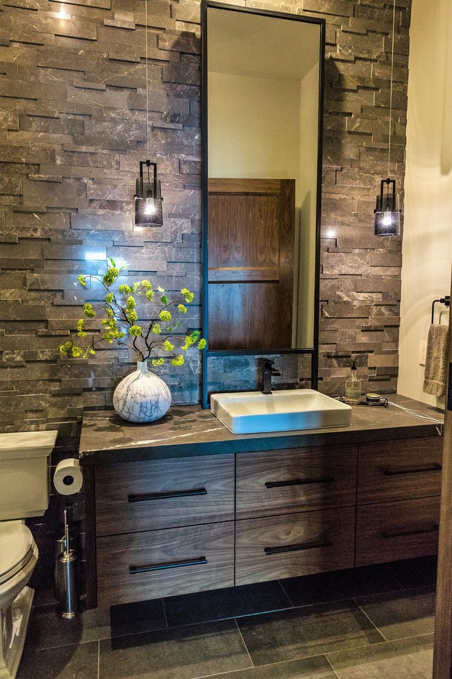 Photo of a large modern powder room in Seattle with flat-panel cabinets, dark wood cabinets, a two-piece toilet, black and white tile, stone tile, beige walls, porcelain floors, a drop-in sink, marble benchtops, grey floor and black benchtops.