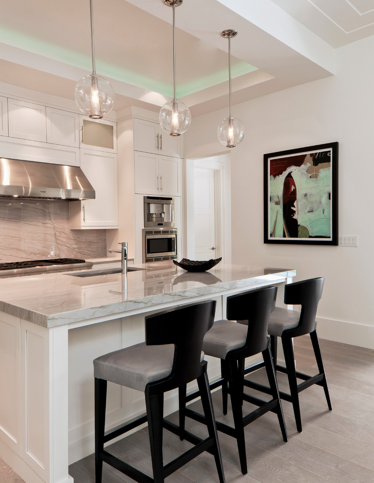 Open concept kitchen - mid-sized transitional u-shaped light wood floor open concept kitchen idea in Miami with an undermount sink, recessed-panel cabinets, white cabinets, granite countertops, gray backsplash, stainless steel appliances and an island