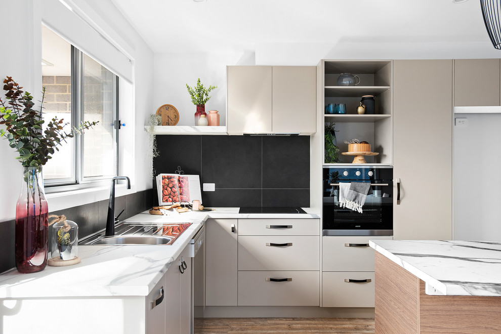Small contemporary galley open plan kitchen in Other with a single-bowl sink, recessed-panel cabinets, grey cabinets, laminate benchtops, black splashback, ceramic splashback, stainless steel appliances, vinyl floors, with island, brown floor and multi-coloured benchtop.