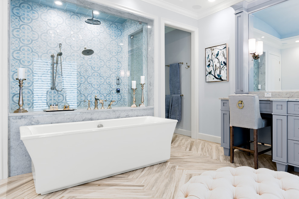 Design ideas for a mid-sized beach style master wet room bathroom in Tampa with shaker cabinets, grey cabinets, a freestanding tub, a two-piece toilet, blue tile, ceramic tile, blue walls, porcelain floors, an undermount sink, marble benchtops, grey floor, a hinged shower door and grey benchtops.