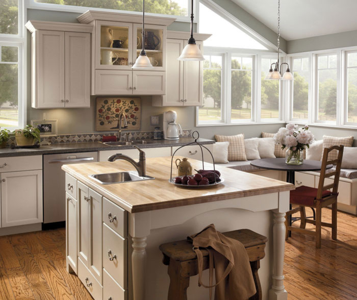 Example of a mid-sized transitional medium tone wood floor and brown floor eat-in kitchen design in Cedar Rapids with a double-bowl sink, shaker cabinets, white cabinets, stainless steel appliances and an island