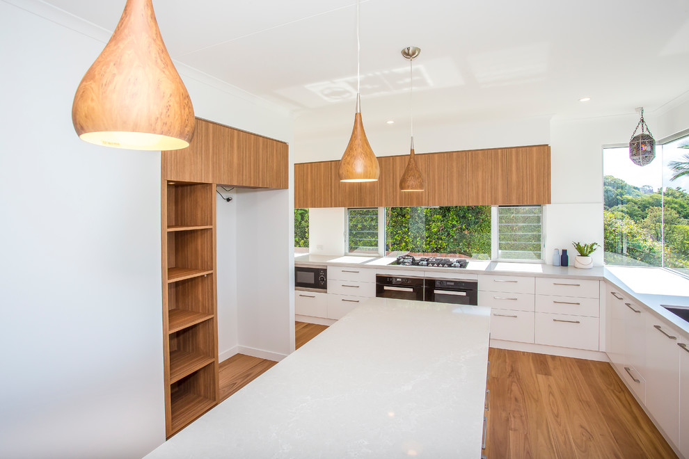 Photo of a large contemporary l-shaped separate kitchen in Sunshine Coast with a double-bowl sink, flat-panel cabinets, white cabinets, quartz benchtops, window splashback, stainless steel appliances, light hardwood floors, with island and brown floor.