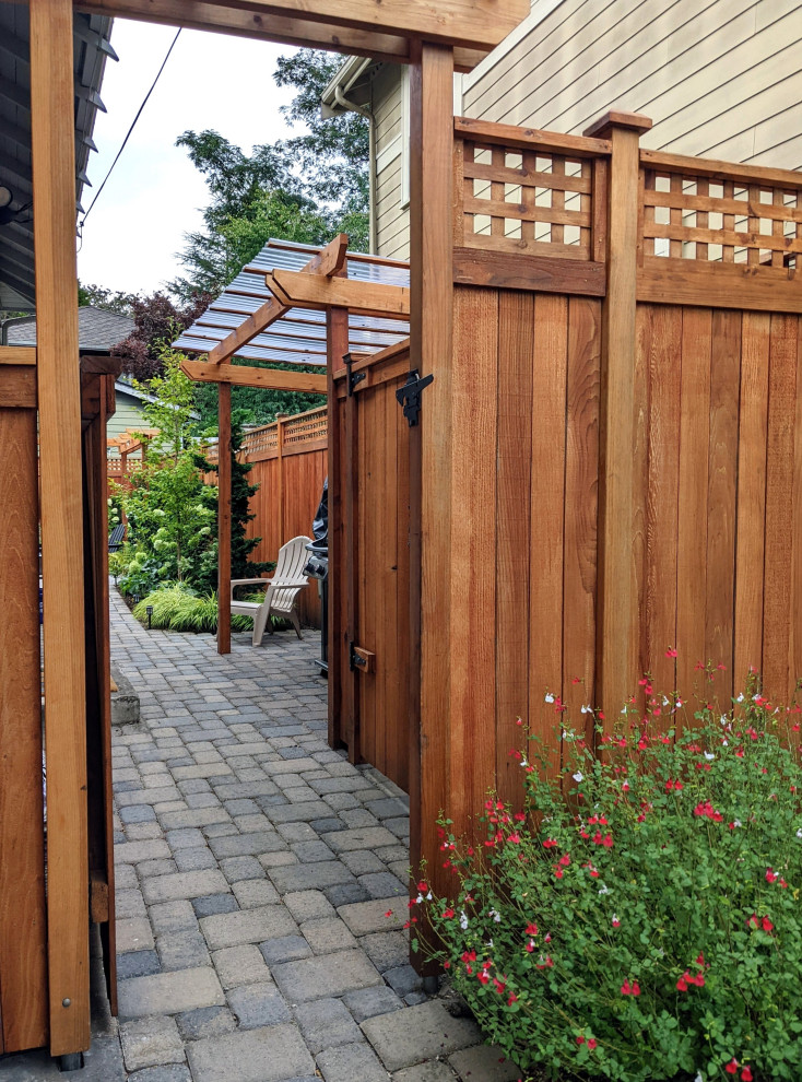 Kleiner, Halbschattiger Uriger Garten neben dem Haus mit Sichtschutz, Betonboden und Holzzaun in Seattle