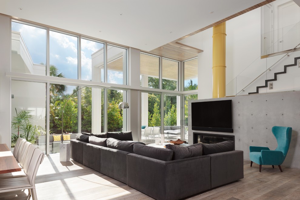 Photo of a contemporary open concept living room in Miami with white walls, medium hardwood floors, a ribbon fireplace, a wall-mounted tv and brown floor.