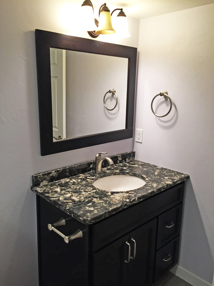 Design ideas for a mid-sized traditional powder room in Other with recessed-panel cabinets, grey walls, dark hardwood floors, an undermount sink, granite benchtops and black cabinets.