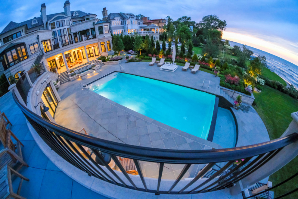 Imagen de piscina alargada clásica de tamaño medio rectangular en patio con paisajismo de piscina y adoquines de piedra natural