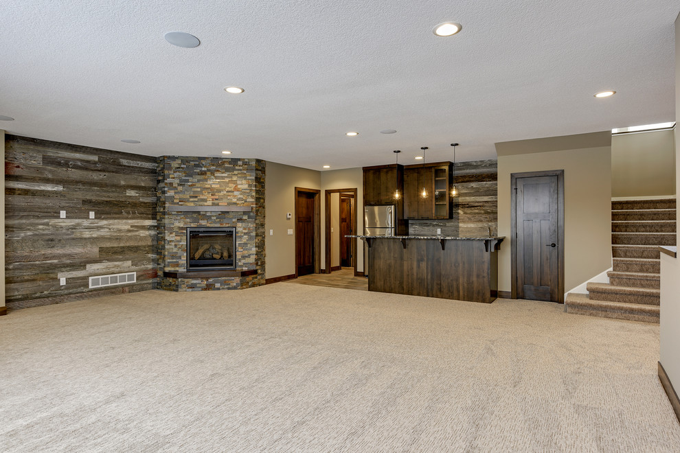 Large contemporary open concept family room in Minneapolis with a home bar, grey walls, carpet, a corner fireplace, a stone fireplace surround, a wall-mounted tv and grey floor.