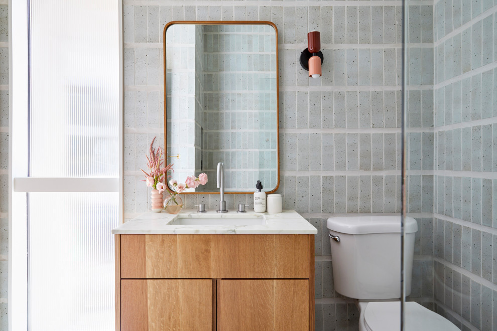 Inredning av ett retro litet vit vitt badrum, med släta luckor, bruna skåp, ett badkar i en alkov, en dusch i en alkov, en toalettstol med separat cisternkåpa, blå kakel, perrakottakakel, blå väggar, klinkergolv i keramik, ett undermonterad handfat, marmorbänkskiva, grönt golv och dusch med gångjärnsdörr