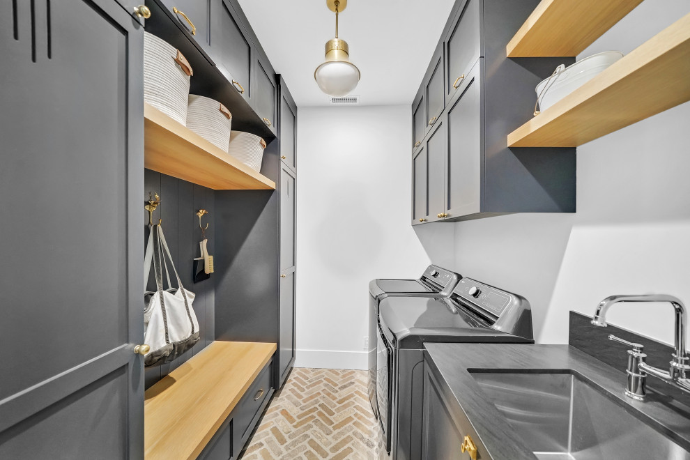 Design ideas for a laundry room in Orange County with a farmhouse sink, grey cabinets, quartz benchtops, grey splashback, engineered quartz splashback, white walls, brick floors, a side-by-side washer and dryer, multi-coloured floor and grey benchtop.